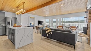A modern kitchen with a marble island, a dining area with a view, and a cozy living space with a fireplace. - Vashon Modern Beachfront Getaway: Pet & Family-Friendly with Stunning Views! (Vashon)
