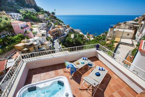A balcony with a hot tub, outdoor seating, and a view of the sea and town. - Medusa Positano (Positano)