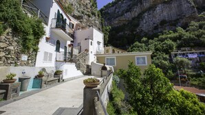 Un bâtiment situé sur la côte, doté de balcons, d’un mur en pierre et de plantes en pot.