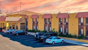A motel with multiple rooms, a parking lot, and a clear sky. - Sun Valley Suites (Bullhead City)