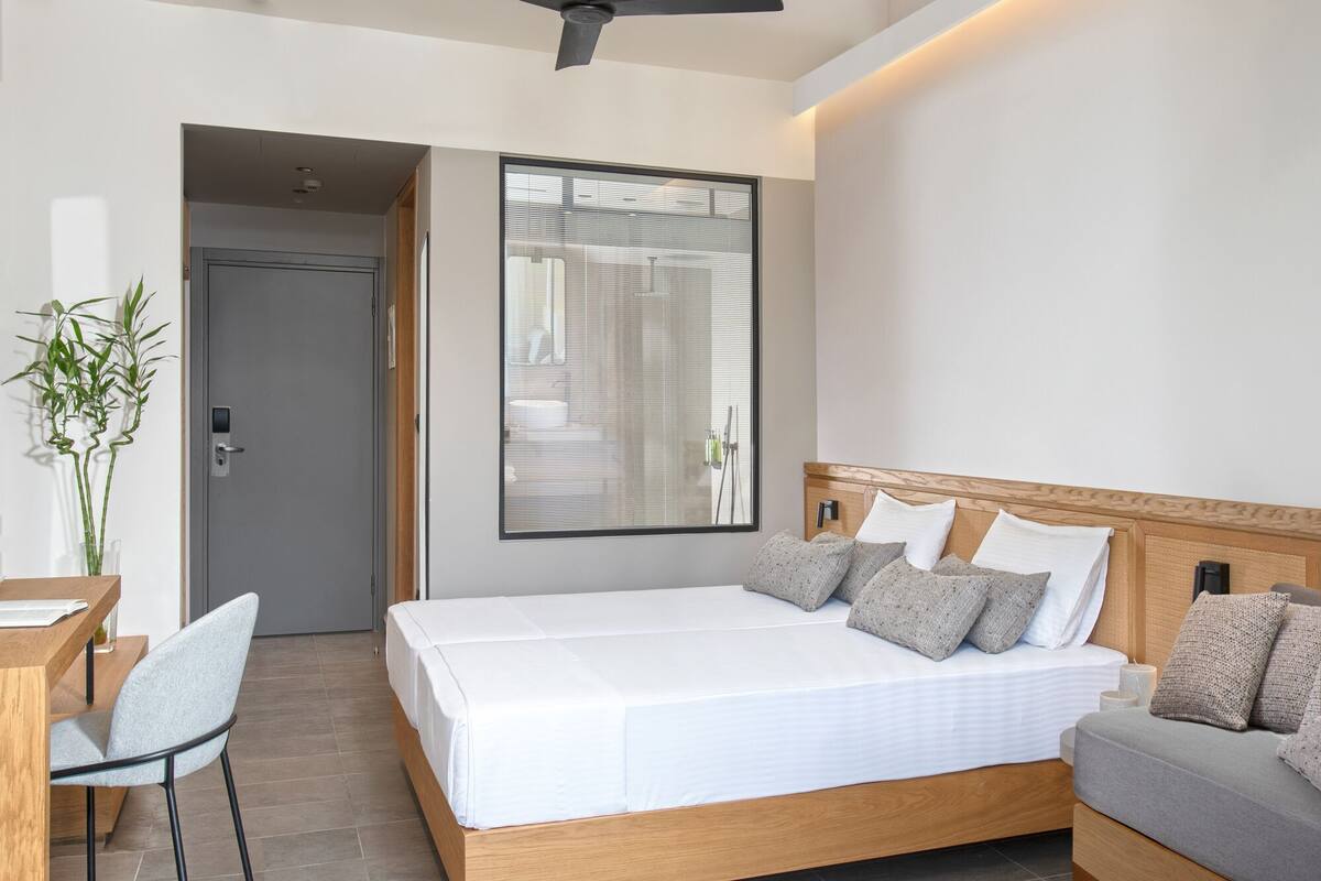 A modern hotel room with a large bed, a desk, and a chair.
