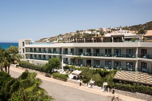 Un hôtel à plusieurs étages doté de balcons, d’un espace piscine et offrant une vue sur la mer.