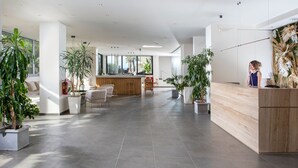 Un hall d’entrée spacieux avec un comptoir d’accueil, un espace salon et des plantes en pot.