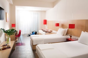 Une chambre d’hôtel avec deux lits, un bureau, une chaise, une plante et une lampe rouge.