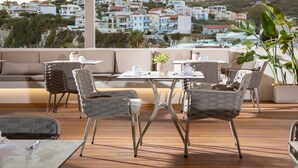 Une terrasse sur le toit, aménagée avec des meubles d’extérieur, notamment un canapé et des fauteuils, ainsi qu’une table dressée pour les repas.