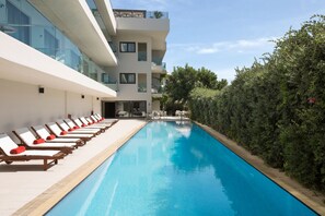 Un hôtel moderne doté d’une piscine, de chaises longues et d’un jardin bien entretenu.