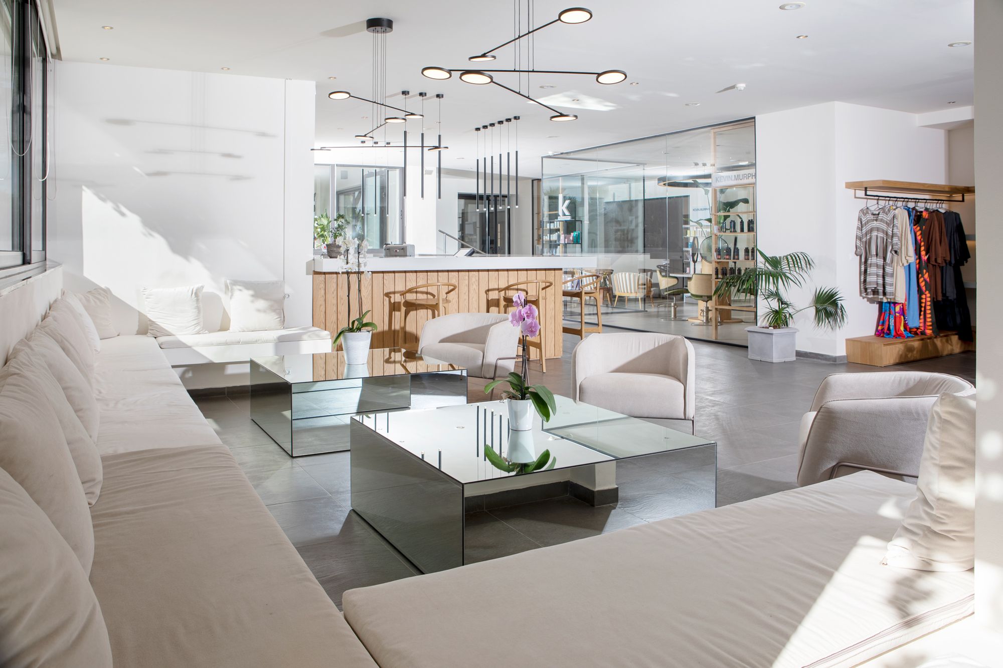 Uma sala de estar moderna com uma mesa de centro de vidro, sofás brancos e um balcão de recepção de madeira.