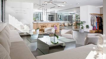 Uma sala de estar moderna com uma mesa de centro de vidro, sofás brancos e um balcão de recepção de madeira.