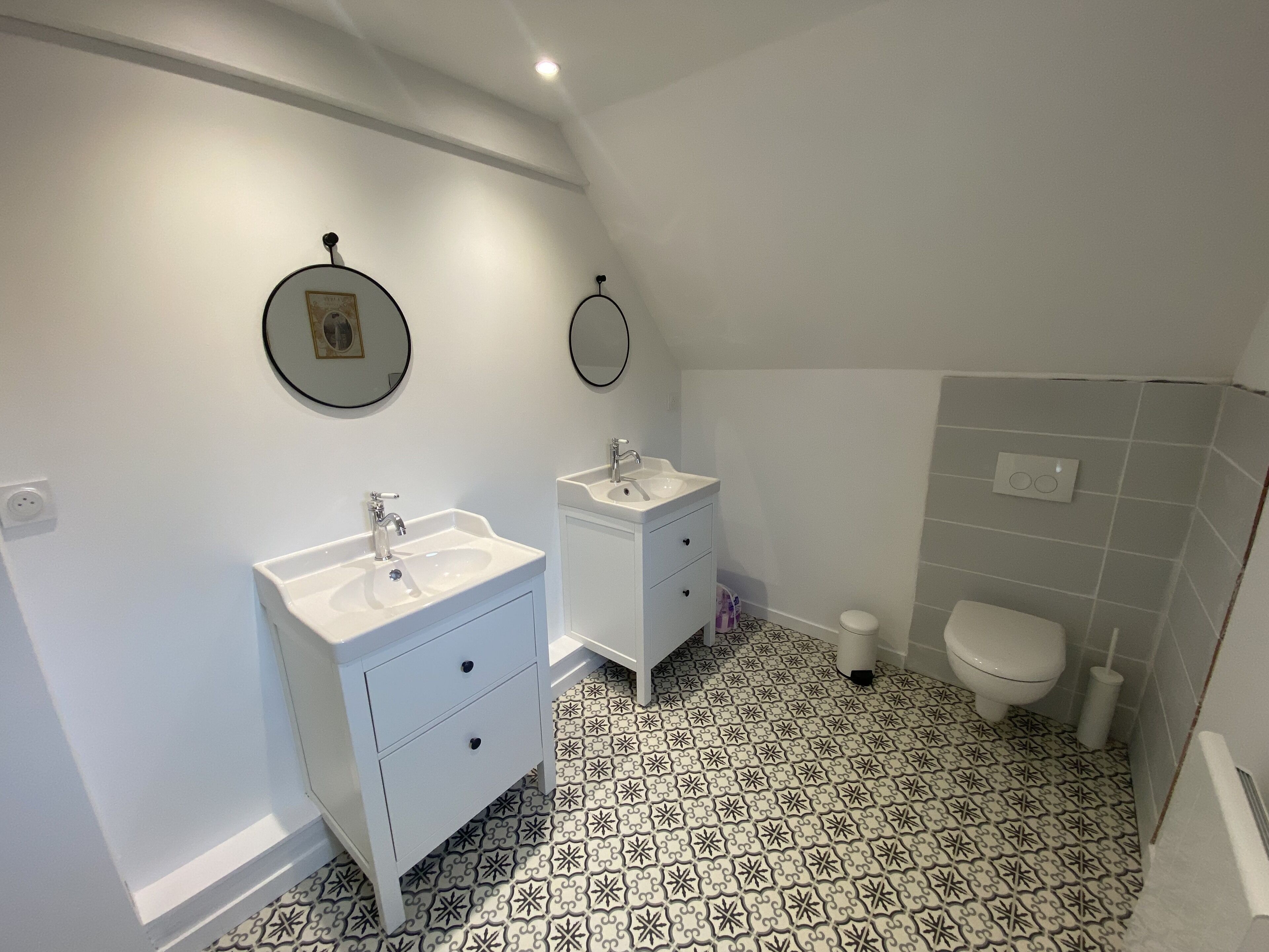 Une salle de bain avec deux lavabos, des toilettes et des carreaux de sol à motifs.