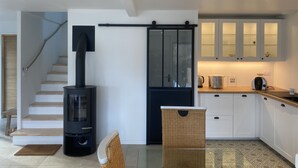 A modern kitchen with white cabinets, a black stove, and a wicker basket. - New ! Family home, 5 minutes from the sea! (La Forêt-Fouesnant)