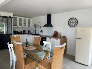 A modern kitchen with white cabinets, a black range hood, and a white refrigerator.