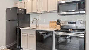 A modern kitchen with a black refrigerator, a dishwasher, a microwave, and an oven. - Relaxing Poolside Condo Steps from the Beach (Hilton Head Island)