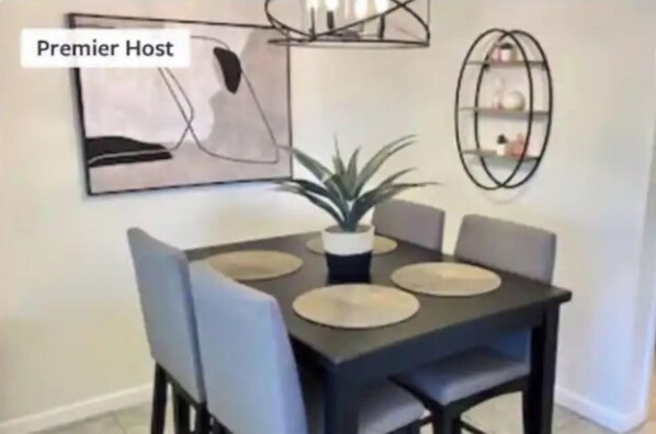 A dining area with a dark table, light blue chairs, and a potted plant. - Casa Del Rio - Across from Rotary Park, River, Boat launch, swimming & fishing (Bullhead City)