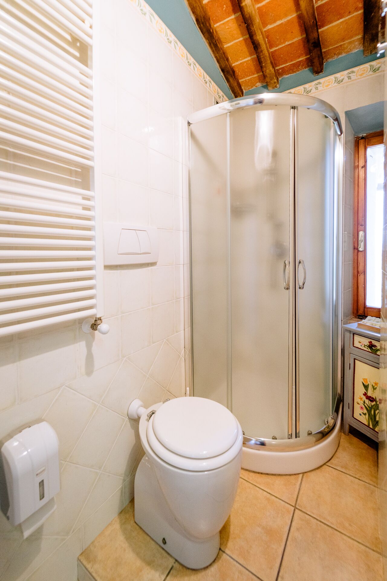 A bathroom with a toilet, a shower enclosure, and a hand dryer.