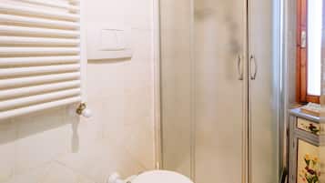 A bathroom with a toilet, a shower enclosure, and a hand dryer.