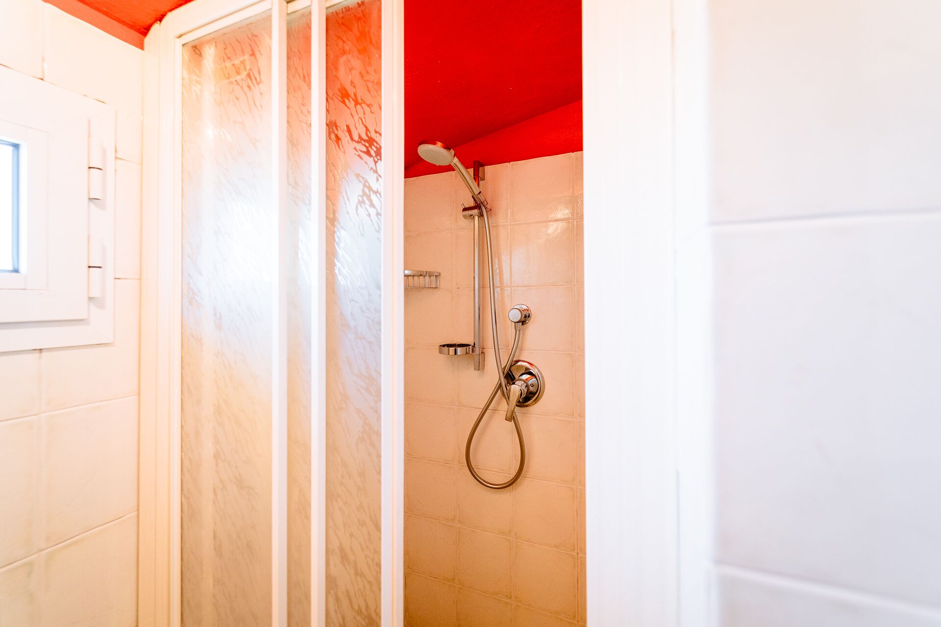 A shower with a handheld showerhead and a wall-mounted faucet.
