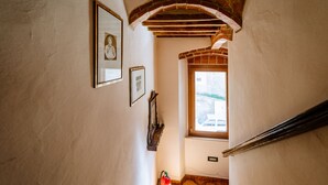 Un pasillo estrecho con un arco de ladrillo, una ventana y cuadros en las paredes.