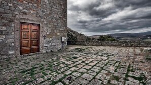 Un edificio de piedra con una puerta de madera y un ventanal circular.