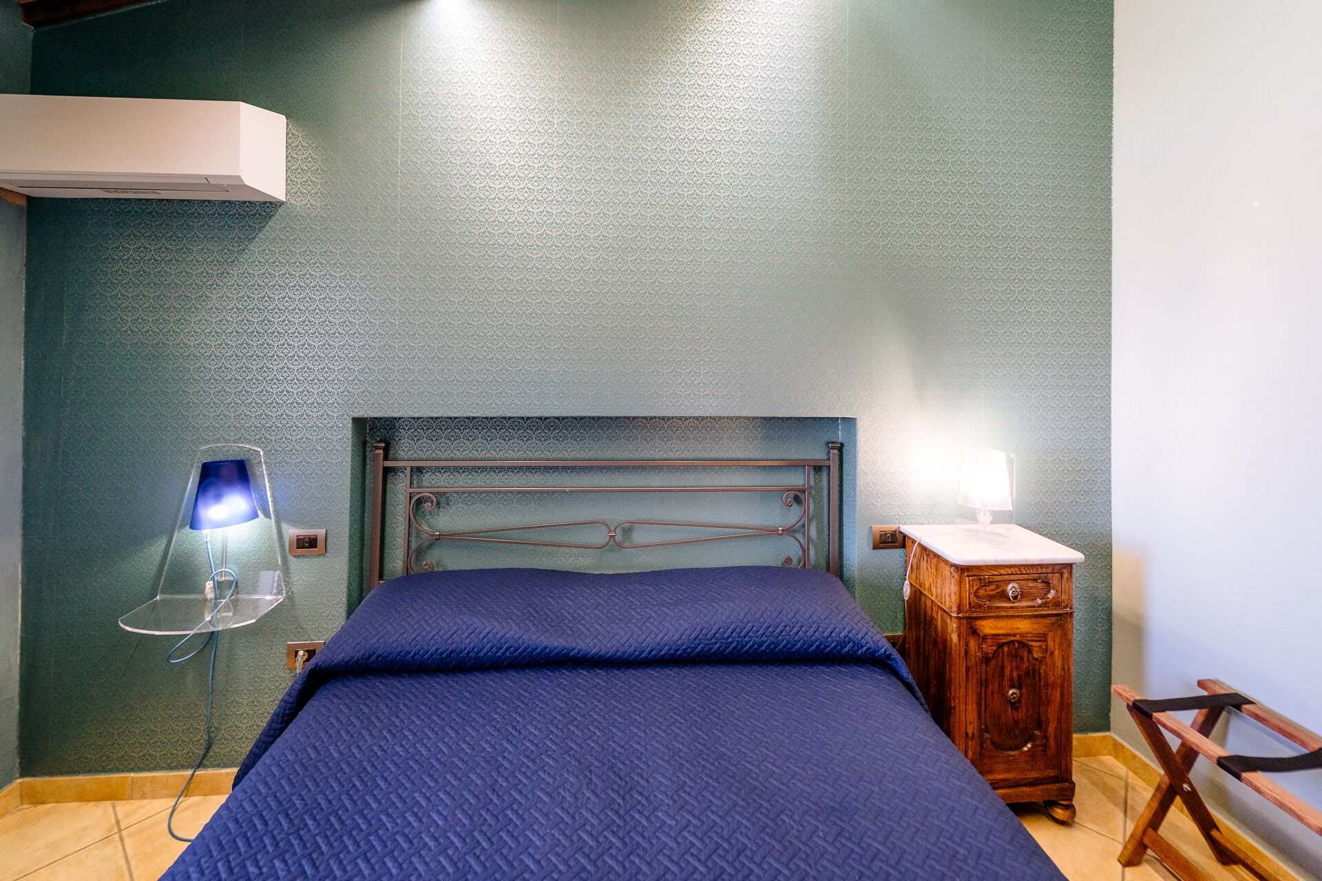 Un dormitorio con cama, mesita de noche, lámpara y cómoda.