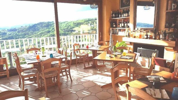 Un restaurante con terraza, una zona de bar y vistas del paisaje.