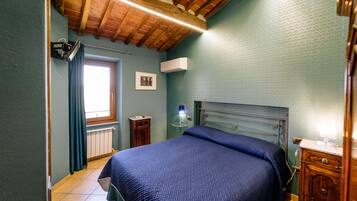 A bedroom with a bed, a radiator, a window, and a wooden ceiling.