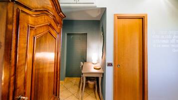 A hallway with a wooden door, a small table with a lamp, and a tiled floor.