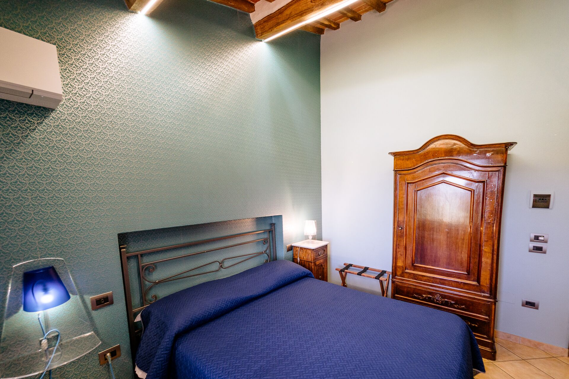 Un dormitorio con una cama, un armario de madera, una mesita de noche y una lámpara.