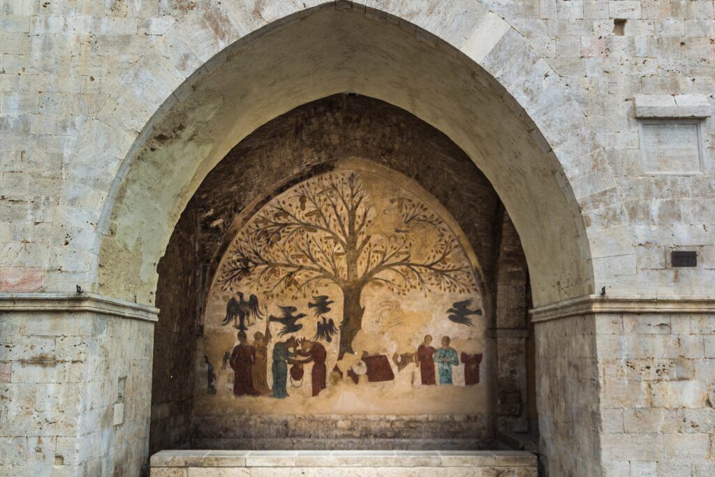 A stone archway with a mural depicting a tree and figures.