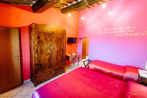 Una habitación con un armario de madera, una cama con ropa de cama roja, un escritorio con una silla y una pared con una cita en italiano.