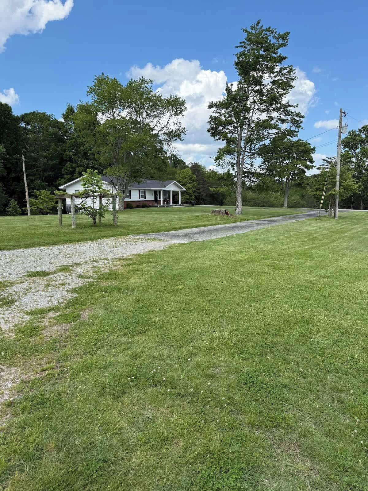 A house with a porch, surrounded by a grassy yard and trees.