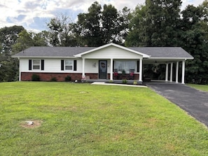 A single-story house with a front porch, a brick foundation, and a grassy yard.