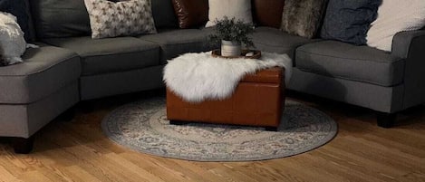 Un salon avec un canapé d’angle, une table basse ronde et un tapis moelleux.