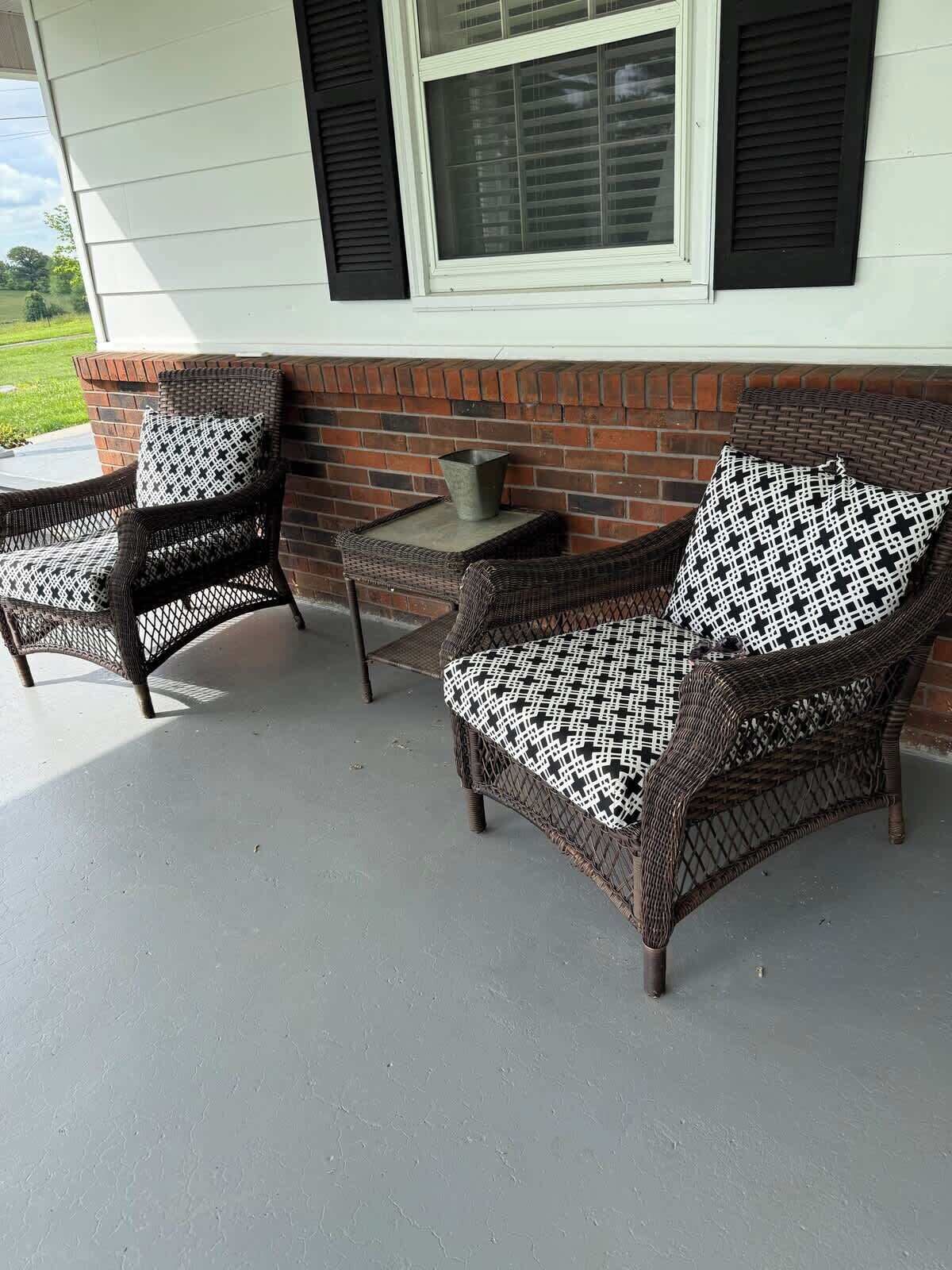 Un patio couvert aménagé avec des meubles en osier et une petite table.