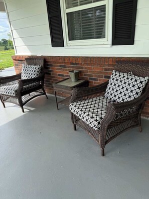 A covered patio area with wicker furniture and a small table.