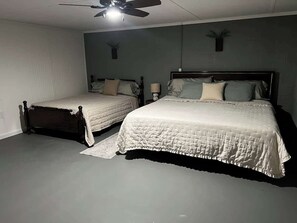 A bedroom with two beds, a ceiling fan, and a wall-mounted lamp.