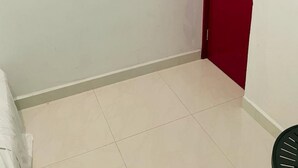 Una habitación pequeña y limpia, con una puerta roja y paredes blancas.