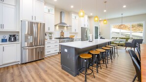 A modern kitchen with stainless steel appliances, a central island with stools, and pendant lighting. - 25% late summer discount! Lakefront | 2 slip covered dock | Hot tub | (Speedwell)