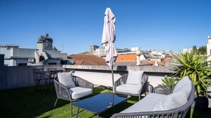 Une terrasse sur le toit, aménagée avec du mobilier d’extérieur, une table et un parasol.