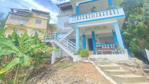 A two-story building with a balcony, stairs leading to the entrance, and potted plants. - The Water Melon House (Samaná)