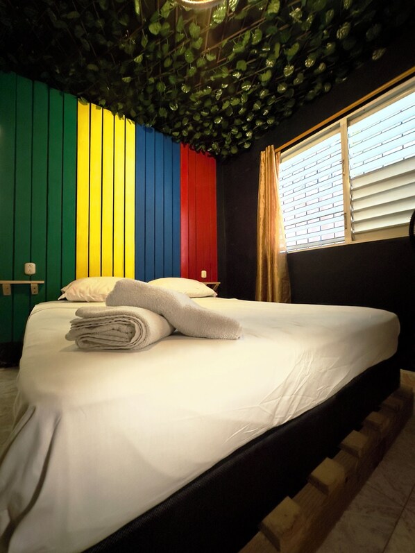 A bed with white linens and a stack of folded towels. - The Water Melon House (Samaná)