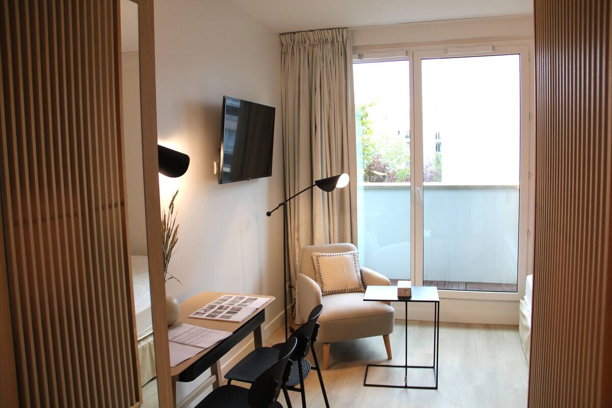 A modern room with a desk, chair, and a TV mounted on the wall.