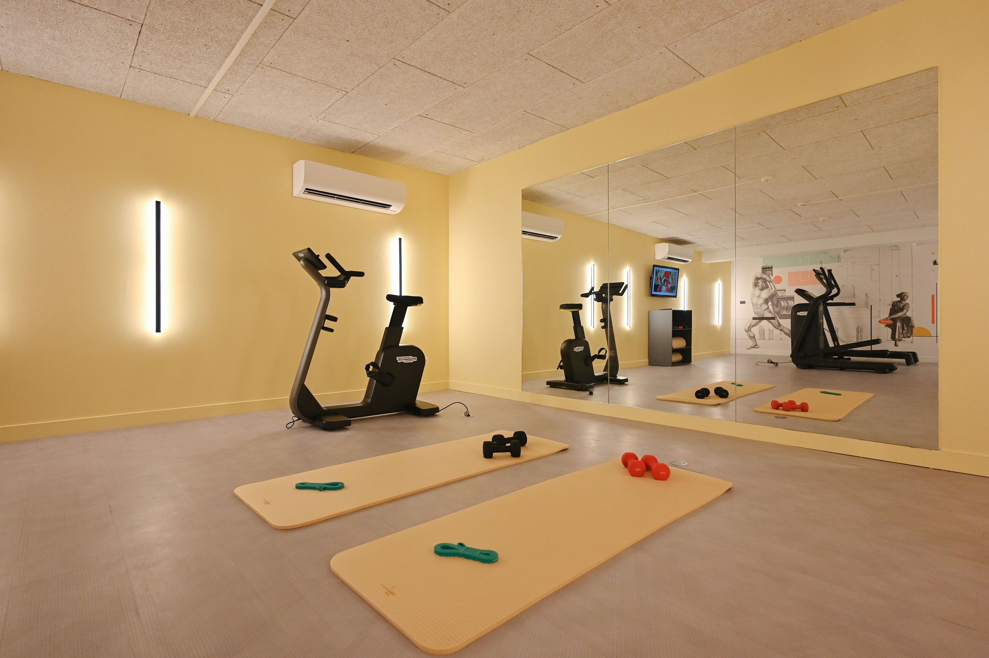 A gym with exercise equipment, mats, and a large mirror.