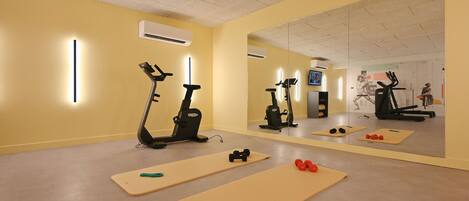 A gym with exercise equipment, mats, and a large mirror.