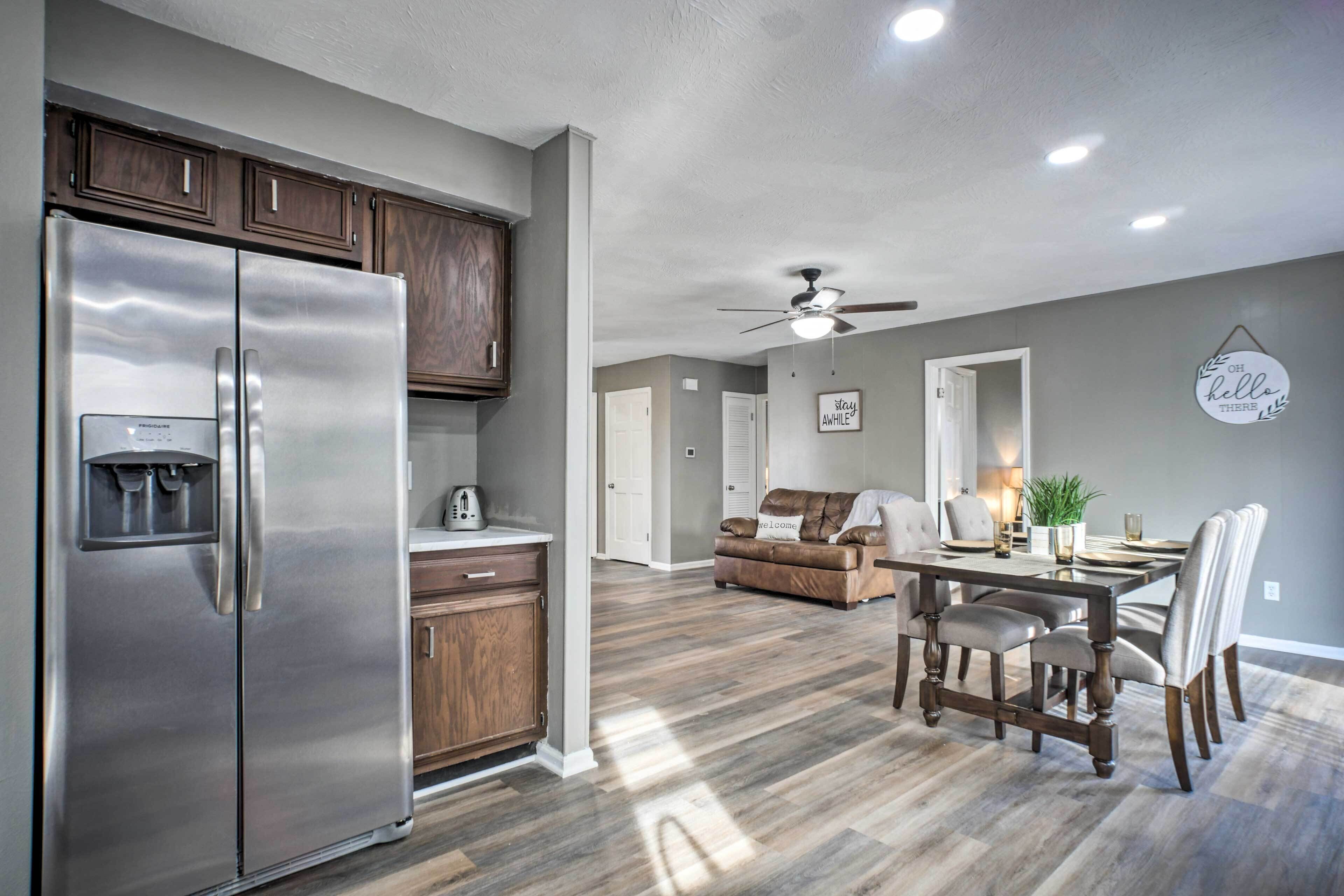 A modern kitchen with a stainless steel refrigerator, wooden cabinets, and a dining area with a wooden table and chairs.