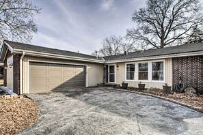 Ein Wohnhaus mit Garage, einer Veranda mit Blumentöpfen und einer Ziegelaußenwand.