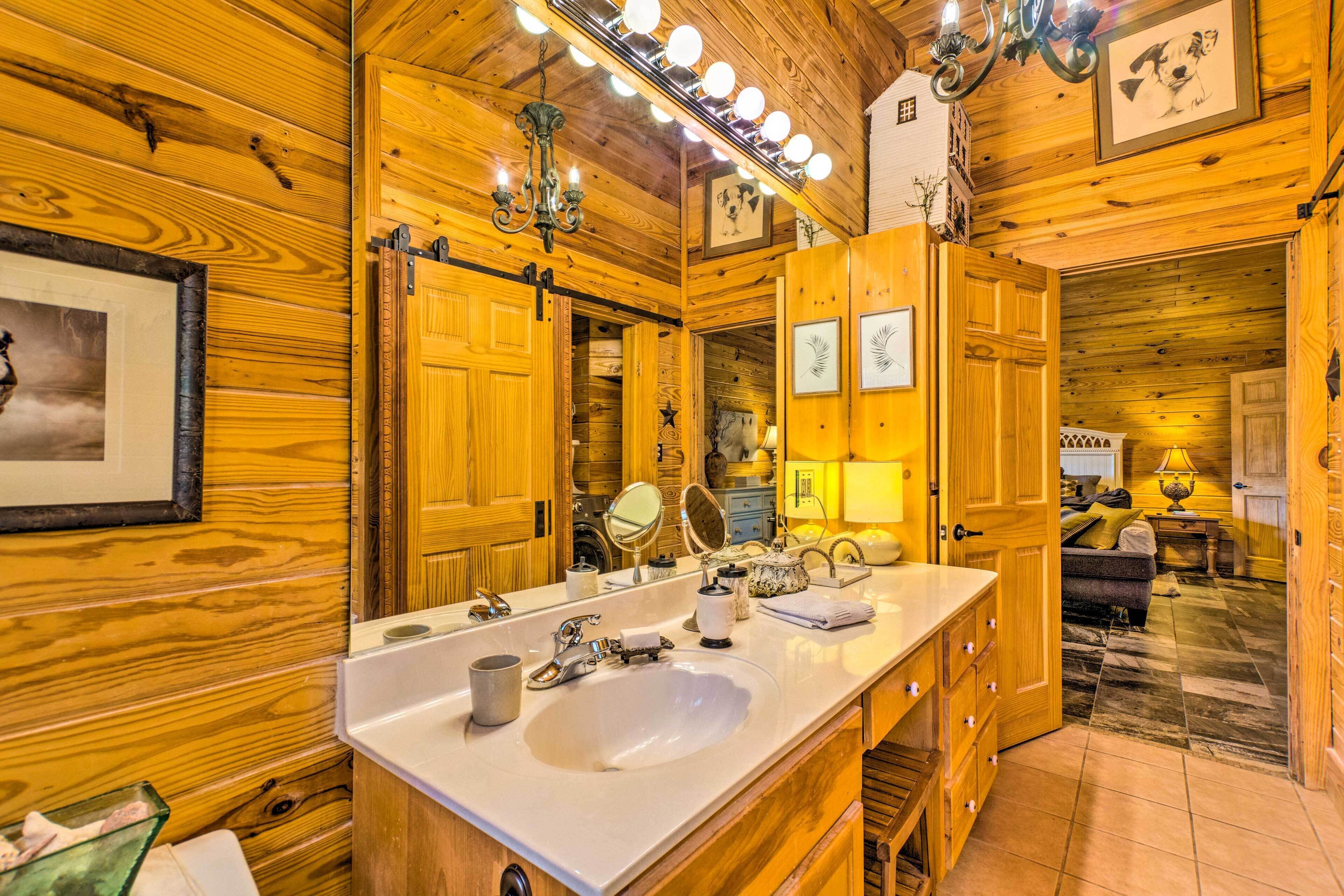Une salle de bain rustique, avec des murs en bois, un grand miroir, un meuble-lavabo et un évier.