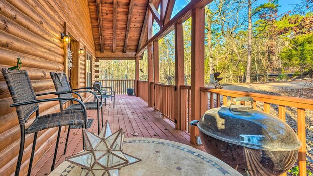 A wooden deck with chairs and a grill, overlooking a forested area. - Pet-Friendly Cabot Cabin w/ Fenced Yard! (Cabot)