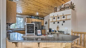 Une cuisine dotée d’un plan de travail en granit, de meubles en bois, d’un tableau noir et d’une machine à café.
