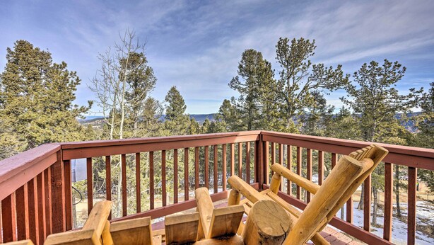 Une terrasse en bois dotée d’une rambarde, qui offre une vue sur un paysage enneigé et des arbres.