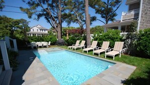A rectangular swimming pool with a tiled deck, surrounded by lounge chairs and a grassy area. - Beach luxury at it's best!! (Rehoboth Beach)